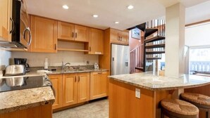 A modern kitchen with wooden cabinets, a stainless steel refrigerator, and a granite countertop. - Condo with Hot Tub Free Garage Parking by RedAwning (Vail)