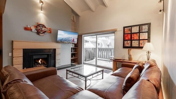 A living room with a fireplace, leather sofas, a coffee table, and a TV. - Condo with Hot Tub Free Garage Parking by RedAwning (Vail)