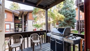 Porxada amb una barbacoa, dues cadires i vista a edificis veïnals.