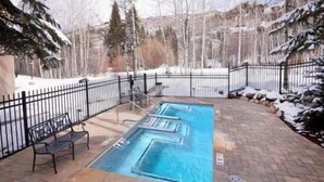 A rectangular swimming pool with steps, surrounded by a brick patio and a black metal fence. - Townsend Place Condo with Ski-In Ski-Out Access by RedAwning (Avon)