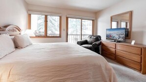 A bedroom with a large bed, a TV, a dresser, and a chair. - Townsend Place Condo with Ski-In Ski-Out Access by RedAwning (Avon)
