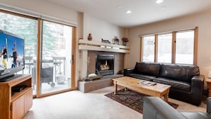 A living room with a fireplace, a leather sofa, a coffee table, and a television. - Townsend Place Condo with Ski-In Ski-Out Access by RedAwning (Avon)