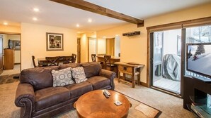 A living room with a brown leather sofa, a wooden coffee table, and a television.