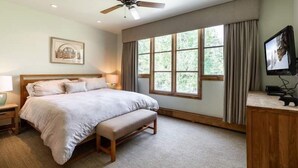 A bedroom with a bed, a ceiling fan, a window with curtains, a bedside table, and a TV. - Ski-in Ski-out Townhome in Beaver Creek by RedAwning (Avon)