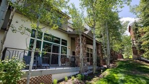 A modern house with large windows, a stone facade, and a well-maintained garden. - Ski-in Ski-out Townhome in Beaver Creek by RedAwning (Avon)
