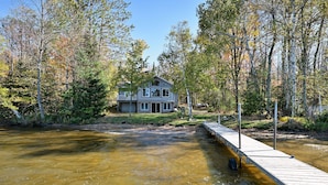 A house by a river with a dock extending into the water.