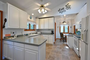 A kitchen with white cabinets, a granite countertop, a ceiling fan, and a chandelier.