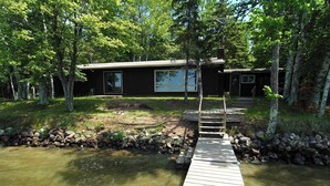 A wooden dock leading to a house surrounded by trees. - Ranch-Style Seidls Home Feet away to Lakeshore by RedAwning (Cable)