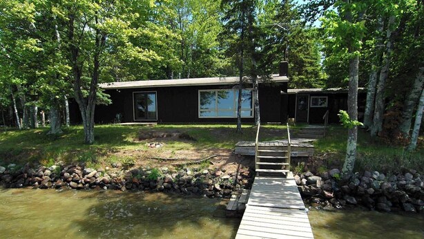 A wooden dock leading to a house surrounded by trees. - Ranch-Style Seidls Home Feet away to Lakeshore by RedAwning (Cable)