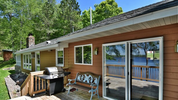 A house with a deck, a grill, and a bench. - Butler's Bay Teal Lake 4 Bedroom Hotel Room by RedAwning (Hayward)