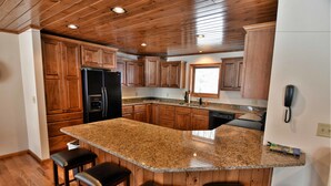 A kitchen with wooden cabinets, a granite countertop, and a built-in island with bar stools.