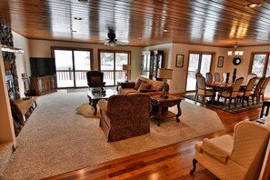 A spacious living room with a fireplace, wooden flooring, and large windows. - Peace Of Mind On Namakagon 5 Bedroom Hotel Room by RedAwning (Cable)