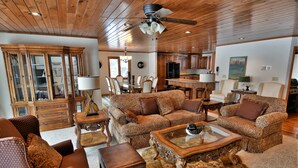 A spacious living room with a large sofa set, a coffee table, and a dining area with chairs and a table.