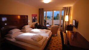 A hotel room with two beds, a small table, a chair, a lamp, and a window with a view of the outdoors. - Das Moerisch (Seeboden)