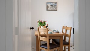 A dining table with chairs, a vase of flowers, and a wine bottle. - WINDYRIG, Cockburnspath - sleeps 4 in 2 bedrooms (Cockburnspath)
