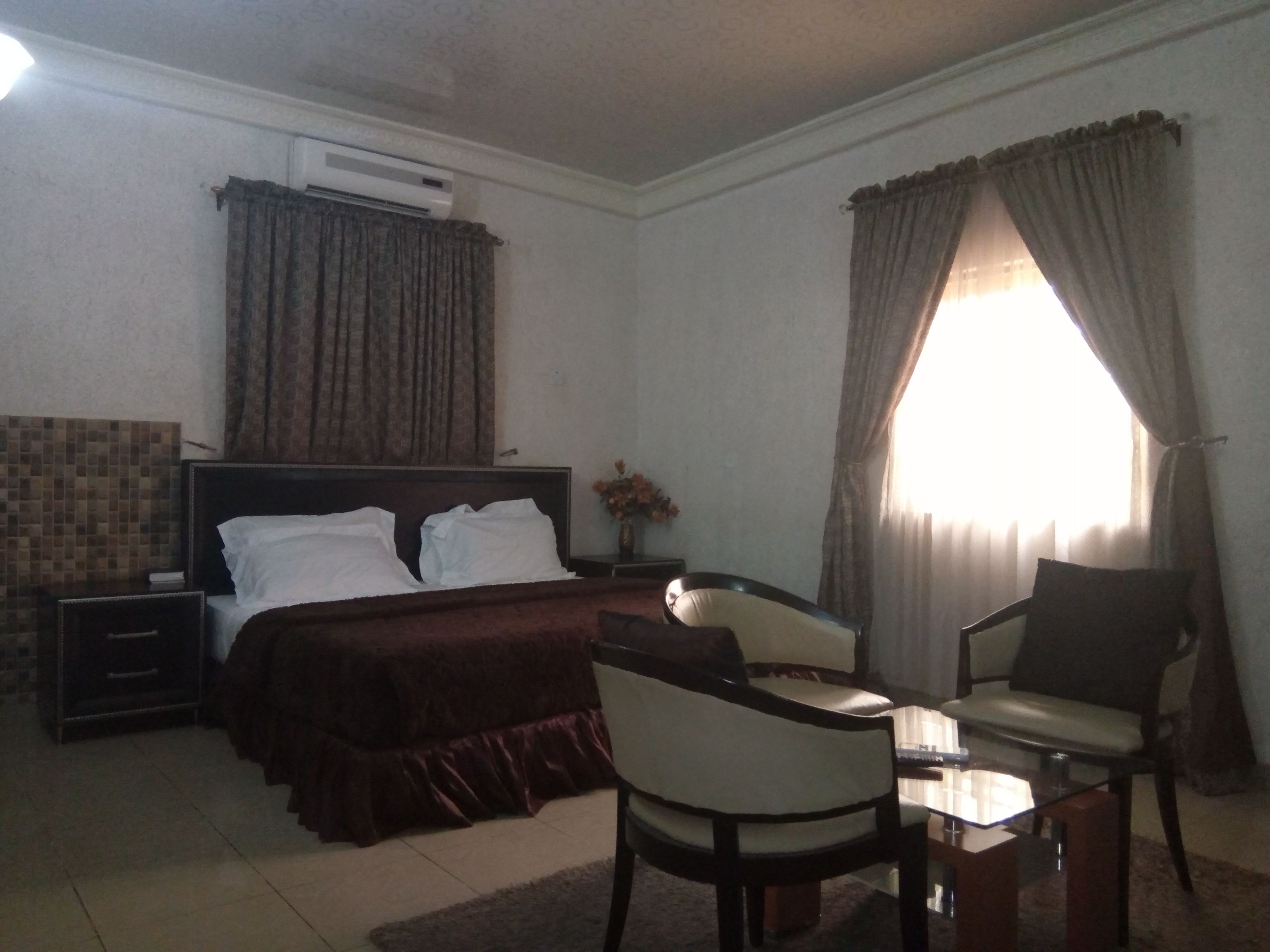 Ein Hotelzimmer mit Bett, Nachttisch, Stuhl und kleinem Tisch.