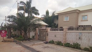 A gated entrance with a sign for Rila Mutam Castle Hotel, a paved pathway, and a building with a tiled roof. - Rila Muam Castle Hotel (Kaduna)