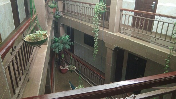 A multi-level atrium with hanging planters and a staircase. - Rila Muam Castle Hotel (Kaduna)