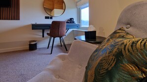 A modern bedroom with a round mirror, a desk, and a comfortable chair. - The Dorset Golf Hotel (Wareham)