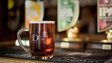 A glass mug with "The Dorset Golf & Country Club" logo on a bar counter.
