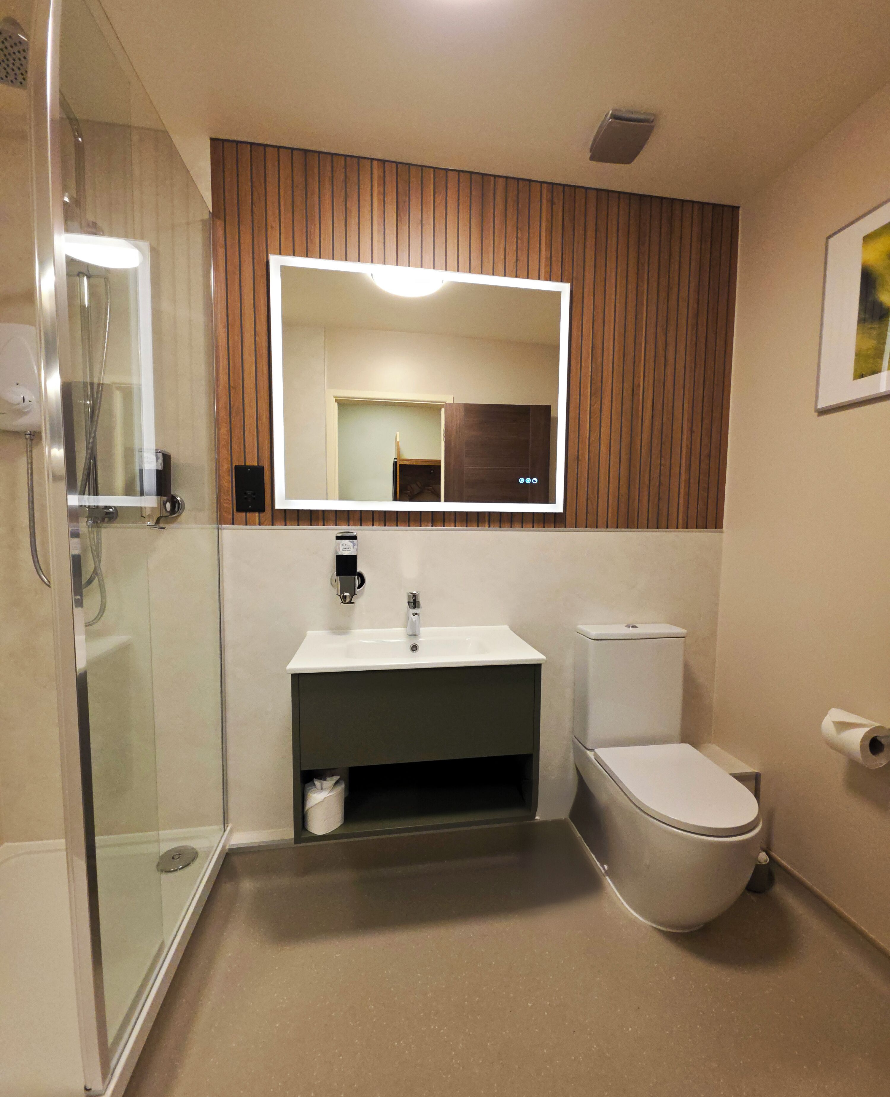 A bathroom with a glass shower enclosure, a sink with a mirror above, and a toilet.
