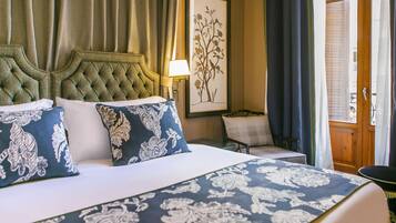 A hotel room with a large bed, a chair, a lamp, and a painting on the wall.