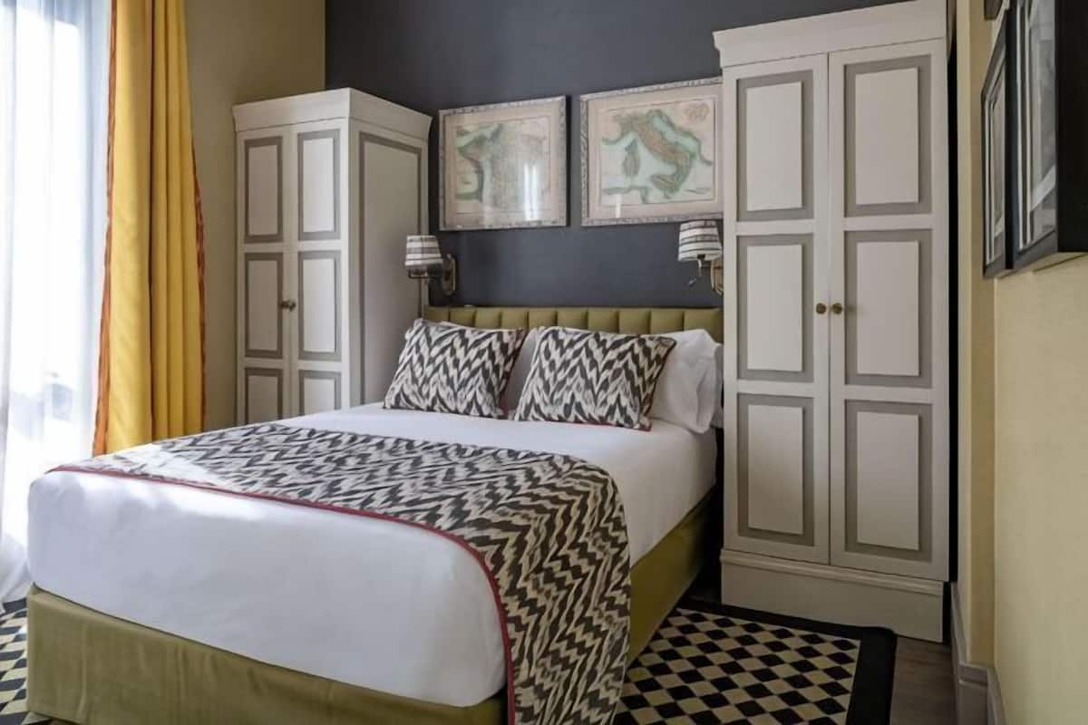 A bedroom with a bed, a wardrobe, and two wall-mounted lamps.