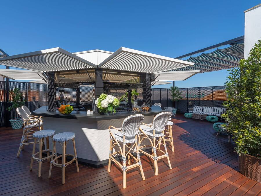Una terraza con barra, sillas de mimbre y un sofá.