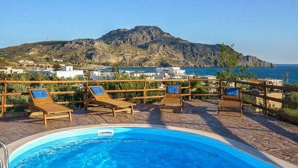 Un área junto a la piscina con sillones de descanso y vistas al mar y a la montaña.