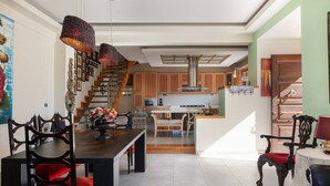 Una cocina amplia con armarios de madera, una isla central y una escalera que conduce a un nivel superior.