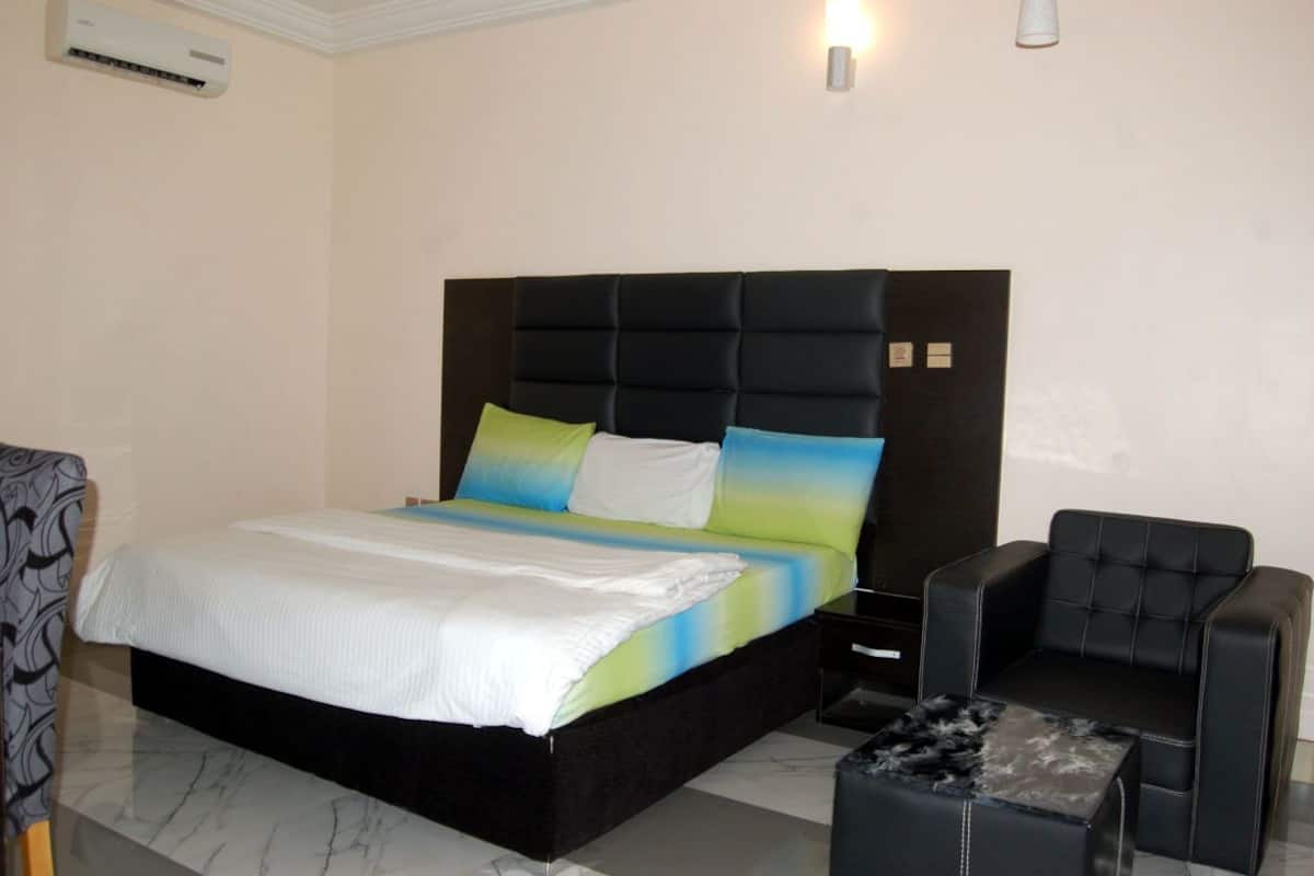 A bedroom with a bed, a nightstand, a chair, and a small table.