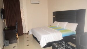 Une chambre d’hôtel équipée d’un lit, d’un bureau, d’une chaise, d’un climatiseur et d’une poubelle.