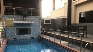 Une piscine intérieure dont les murs sont recouverts de carreaux décoratifs et qui est bordée d’une rambarde en métal.