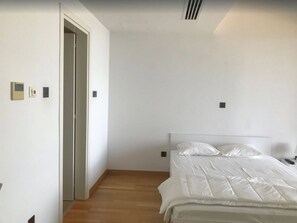 A bedroom with a bed, a door, and a light switch on the wall. - Finikoudes Luxury Apartments (Larnaca)