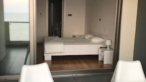 Una camera da letto moderna con un letto, un comodino e vista panoramica attraverso una porta vetrata.