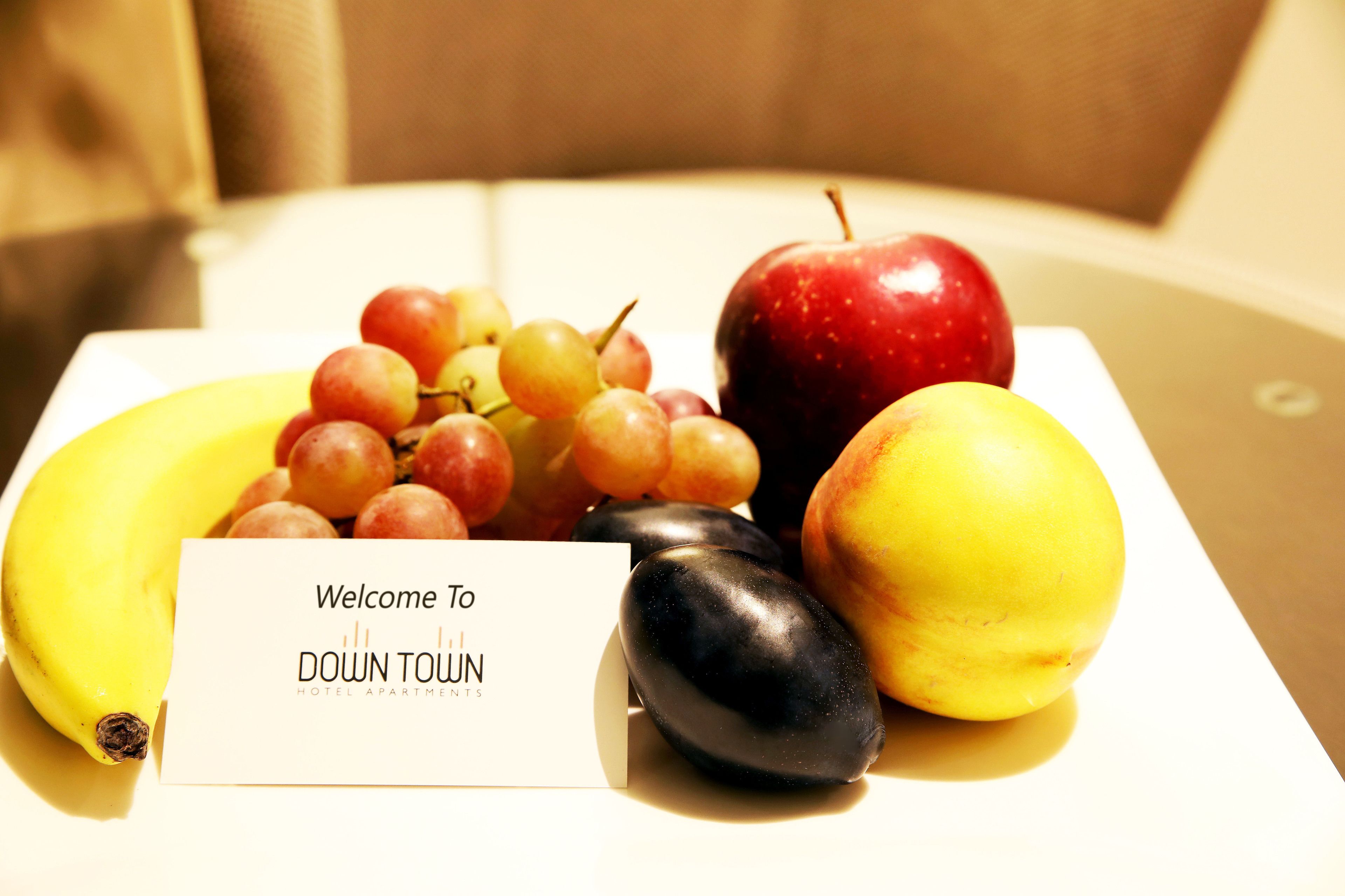 Una bandeja de frutas con un cartel de bienvenida para Down Town Hotel Apartments.