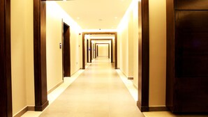 Et hotel med en lang gang, døre i række, flisegulv og en træramme ved indgangen.