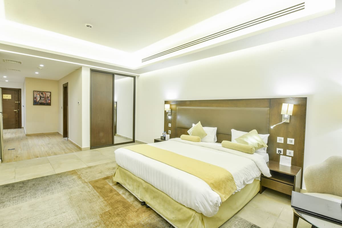 A modern hotel room with a large bed, bedside tables, a desk, and a chair.