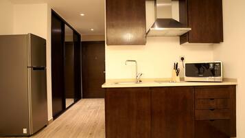 A modern kitchen with a stainless steel refrigerator, a microwave, and wooden cabinets.