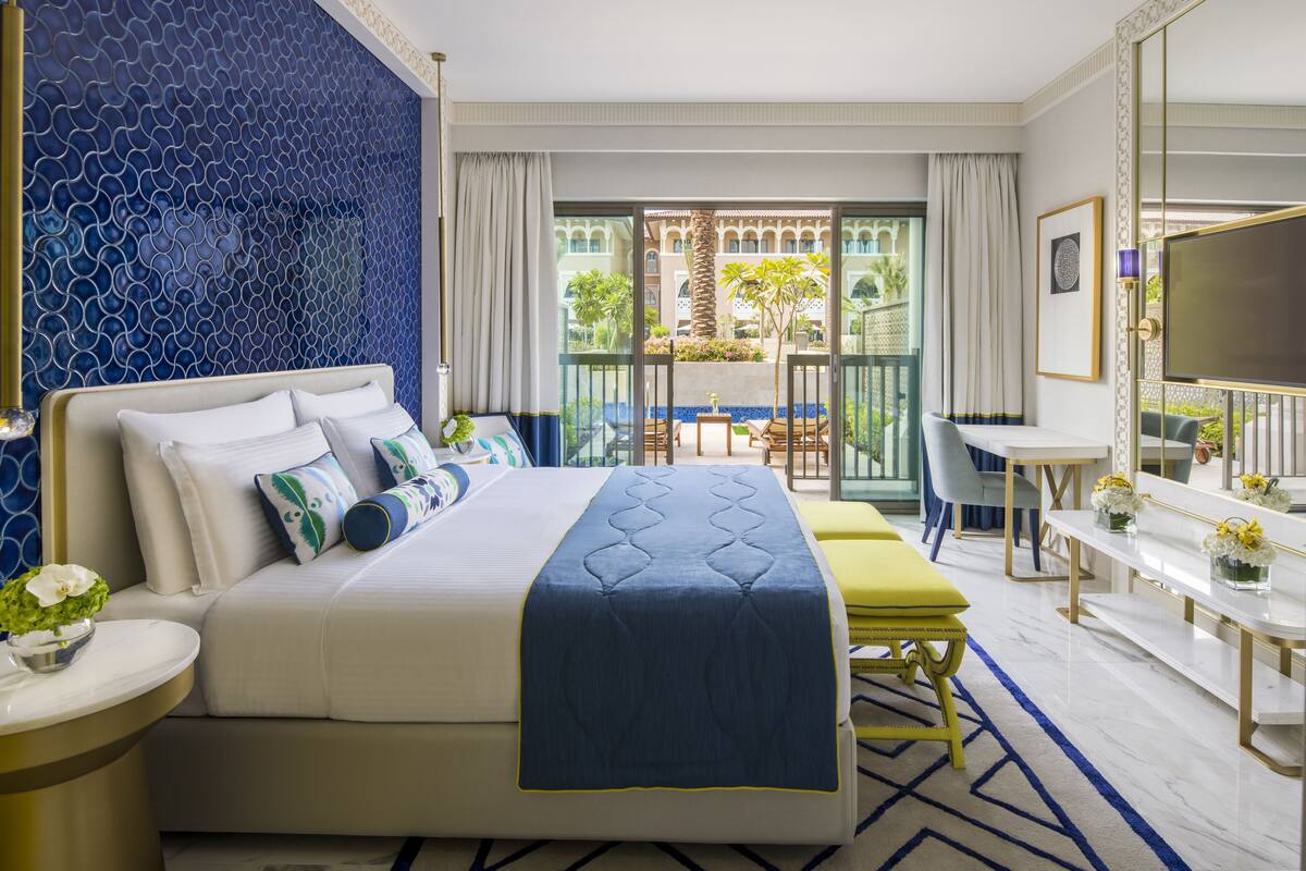 Une chambre d’hôtel comprenant un lit, un bureau, une chaise, un balcon avec vue sur la verdure et une télévision.