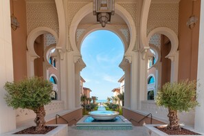 A courtyard with a fountain, palm trees, and arched walkways. - Rixos Premium Saadiyat Island - All inclusive (Abu Dhabi)