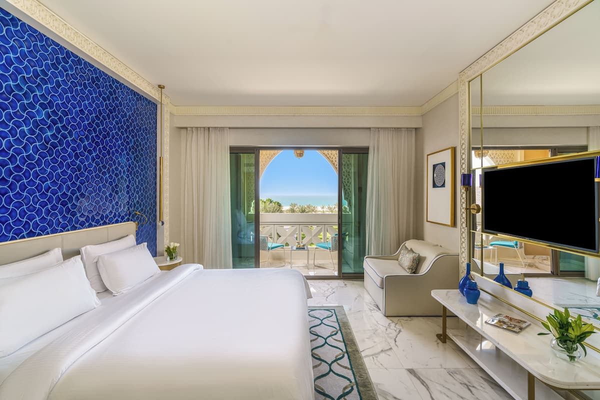 Une chambre d’hôtel avec un lit, un bureau, une télévision et une vue sur l’océan.