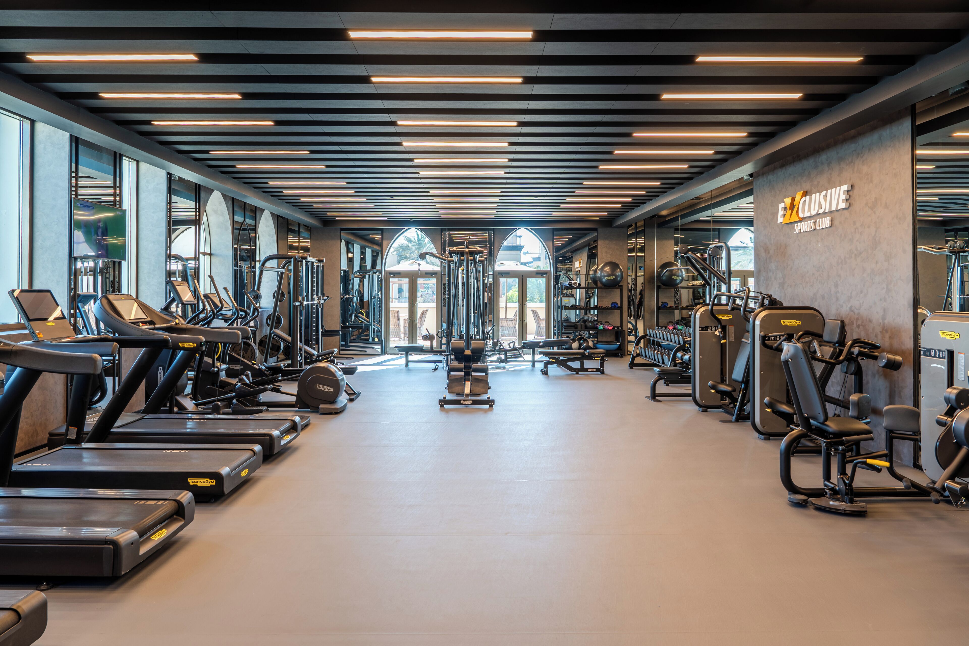 Une salle de sport moderne équipée de tapis de course, de vélos elliptiques et de matériel de musculation.