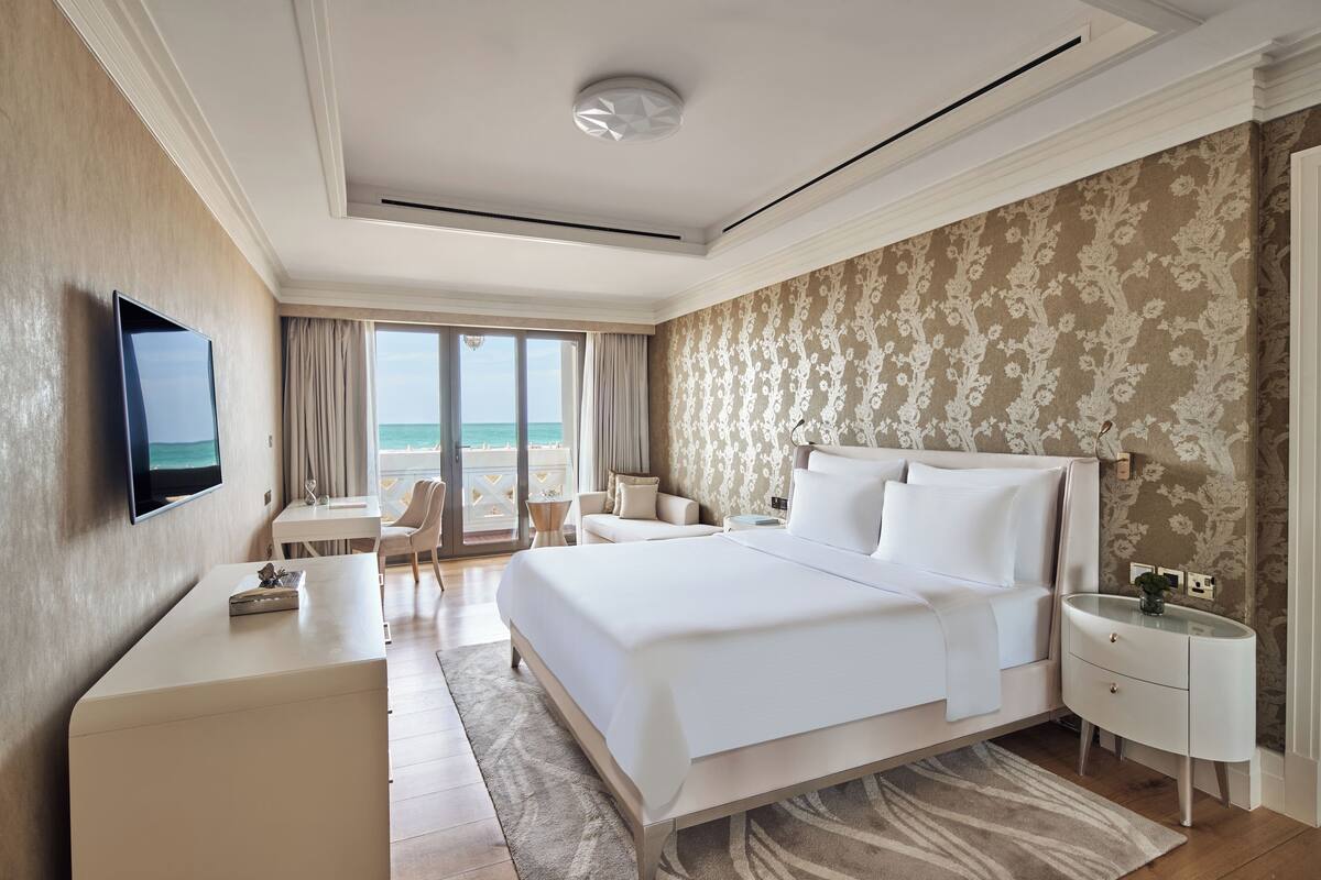 Une chambre d’hôtel moderne dotée d’un grand lit, d’une télévision, d’un bureau et offrant une vue sur la mer.