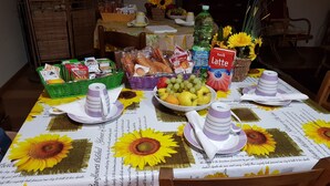 Una mesa de comedor lista con mantel floral, diferentes alimentos y una botella de agua.