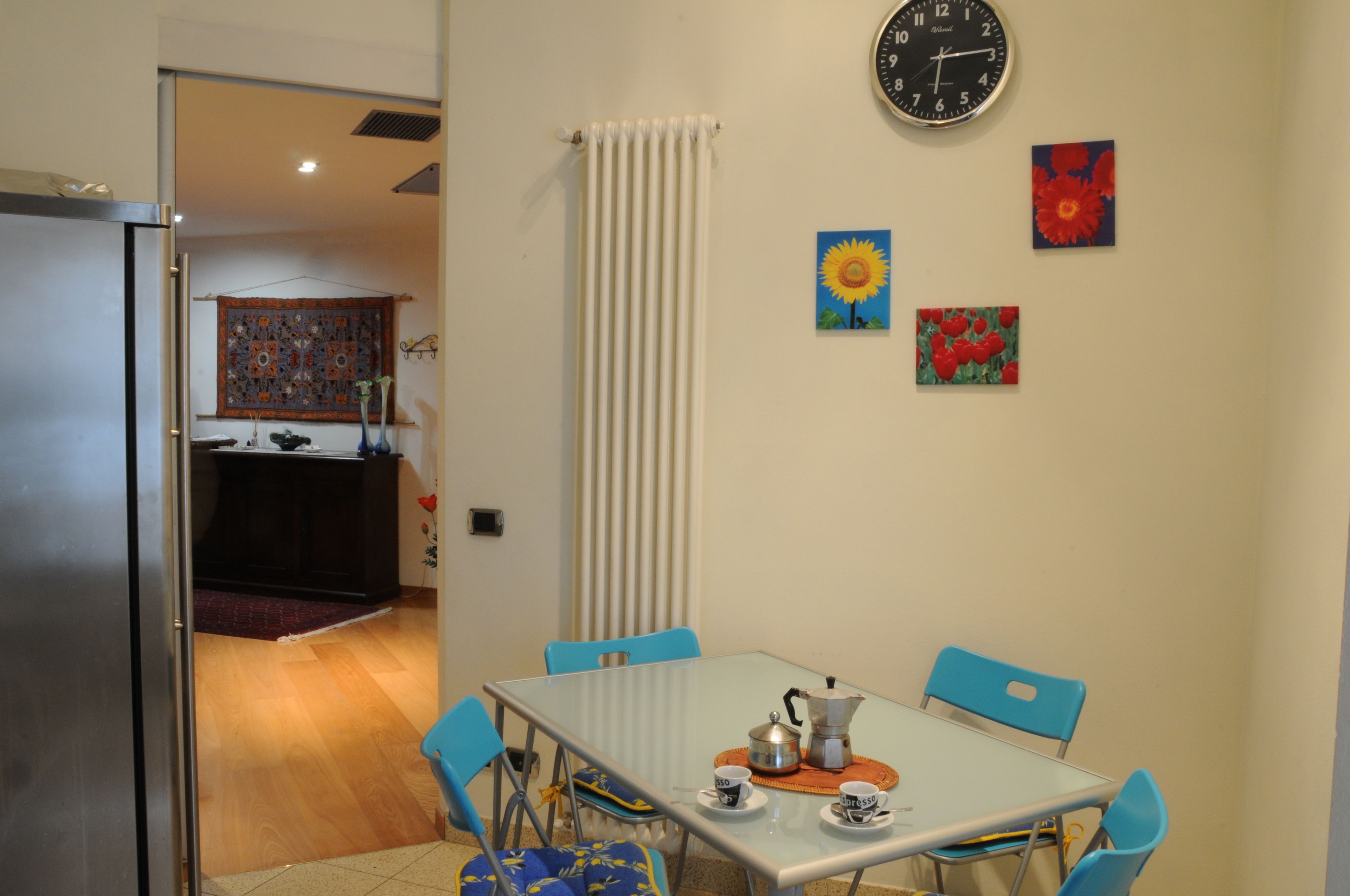 A dining area with a table, chairs, and a clock on the wall.