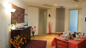 Un comedor con una mesa dispuesta para cuatro personas, un aparador con adornos y una puerta corredera que da a otra habitación.