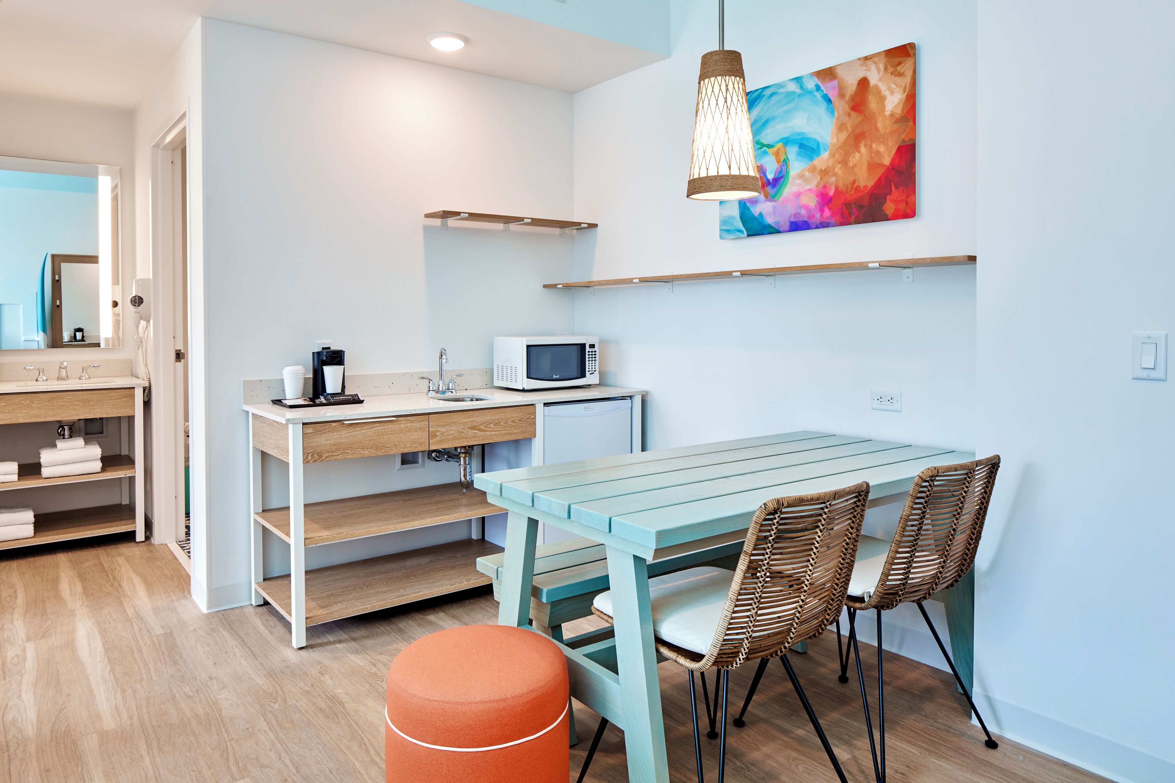 Une cuisine moderne avec un plan de travail en bois, un micro-ondes blanc et une table entourée de chaises en osier.