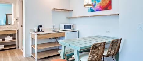 Une cuisine moderne avec un plan de travail en bois, un micro-ondes blanc et une table entourée de chaises en osier.
