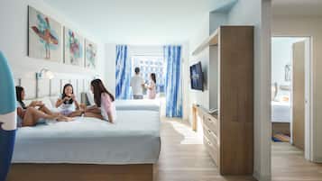 A modern hotel room with a large bed, a TV, and artwork on the walls.